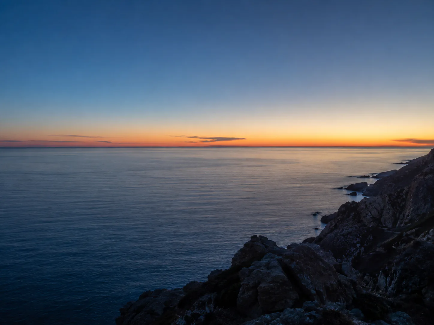 Edited result: Synthetic coastal photo with an orange date stamp over dark rocks, before and after one text-removal edit